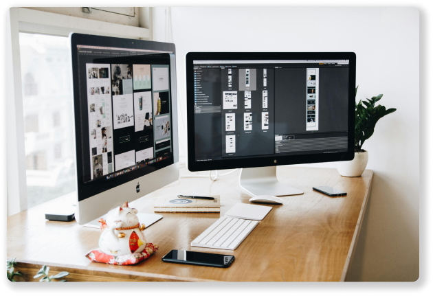 two computer monitors showing website development work